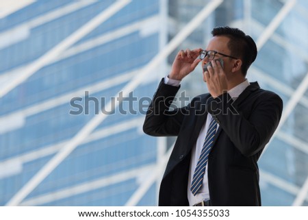 Young Asian businessman sweating due to hot climate. He wiping the face with wet wipes, perspiration, sweat in a city Bangkok Thailand