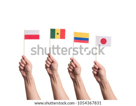 Little paper national flags in hands isolated on white background. Flags of national football teams of Poland, Senegal, Columbia, Japan. World cup competitors in group H Royalty-Free Stock Photo #1054367831