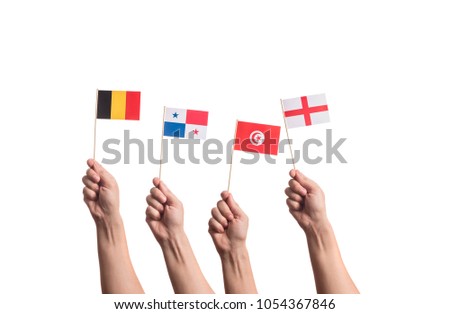 Little paper national flags in hands isolated on white background. Flags of national football teams of Belgium, Panama, Tunisia, England. World cup competitors in group G Royalty-Free Stock Photo #1054367846