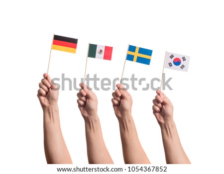 Little paper national flags in hands isolated on white background. Flags of national football teams of Germany, Mexico, Sweden, South Korea. World cup competitors in group F Royalty-Free Stock Photo #1054367852