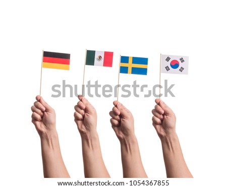 Little paper national flags in hands isolated on white background. Flags of national football teams of Germany, Mexico, Sweden, South Korea. World cup competitors in group F Royalty-Free Stock Photo #1054367855
