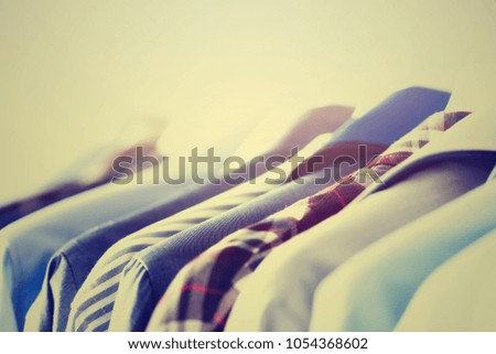 Male clothes, jackets and shirts hanging on clothes rail. Blue color clothes. Copy space. Image with toned effect.