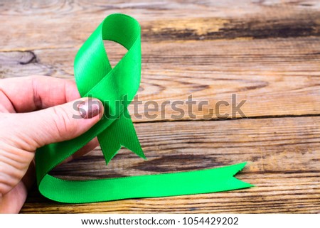 Green ribbon as symbol of awareness of the disease, World Health Day. Studio Photo
