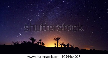 Morocco Sahara desert starry night sky over the oasis. Traveling to Morocco. Glow over the palm trees of the oasis. Billions of stars in the night sky, milky way. Panoramic photo