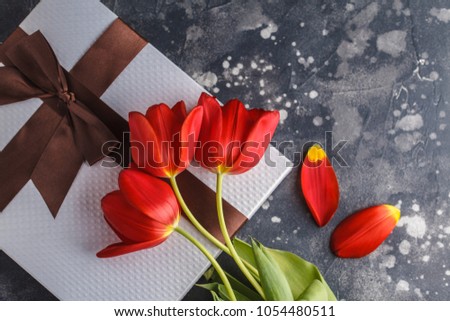 Holiday background. White gift box, red tulips and chocolate-strawberry dessert. Mother's Day / St. Valentine's Day / birthday concept.