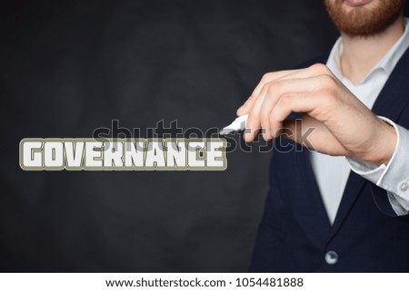 The businessman writes an inscription with a white marker:GOVERNANCE