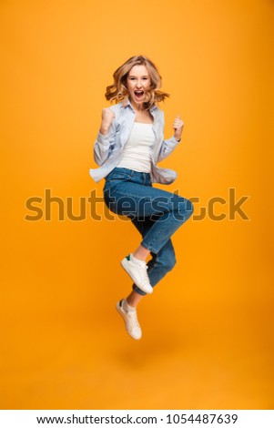 Full length picture of content ecstatic adult girl expressing delight and clenching fists isolated over yellow background