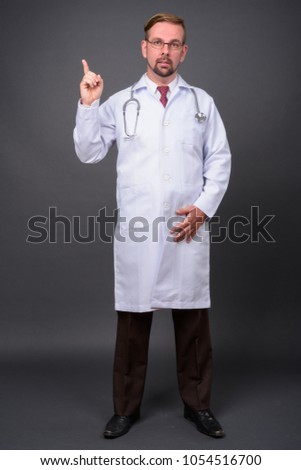 Studio shot of blond bearded man doctor with goatee against gray background