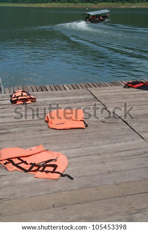 life vest on wood floor with a boat on river background