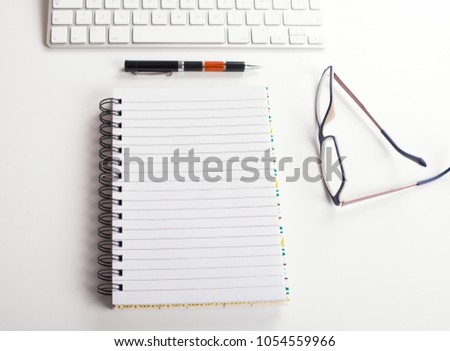 Top view background of workplace with keyboard, notebook, pen and glasses on white background. Business concept Mockup.