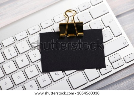 Business car in black color with golden clamp on computer keyboard. Mockup.