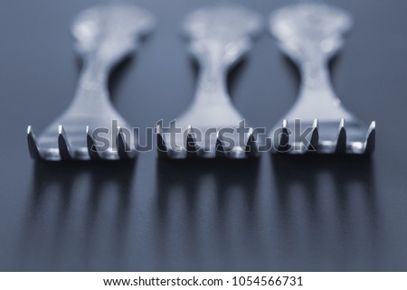 Three forks on a gray background close-up with shallow depth of field, casting shadows