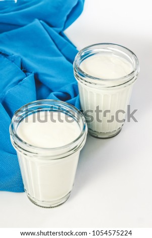 Yoghurt, cream, sour cream in a glass jar and a spoon on a napkin isolated on white background.