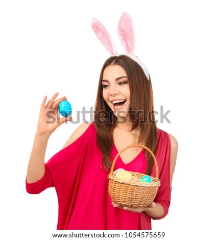 Beautiful young woman with Easter eggs and bunny ears on white background