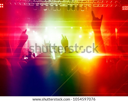 Concert crowd in a colourful venue with a lit stage