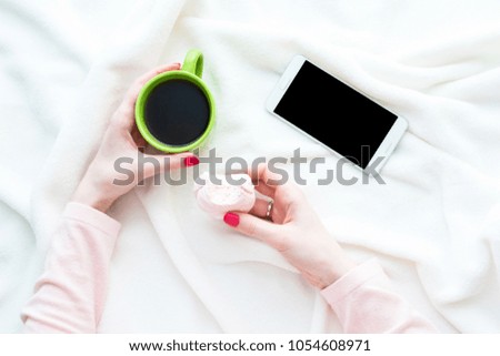 girl uses white smart phone, women's hands, lying on the blanket, white background with copy space, for advertising, top view