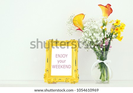 Image of beautiful bouquet of yellow spring flowers next to vintage photo frame over white table