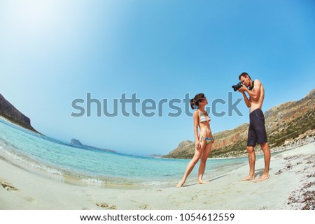 couple walks on the Balos beach on Crete island on a blue sea background. man photographing a woman on the beach. fish eyes shot