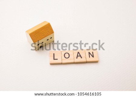 wooden block letters on loan word with house miniature model on white paper background