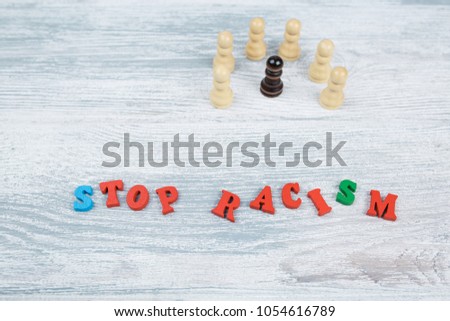 No to racism in colored letters on a gray wooden background, black and white pawn, the concept of the struggle for freedom of human rights