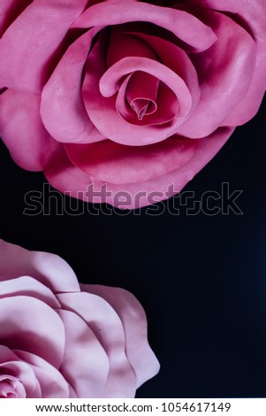 Giant dark-pink handmade foamiran flower at the top og image and light-pink petals on the bottom of black background. Vertical layout. Text space on the bottom.Close up