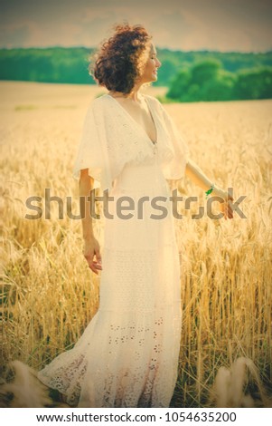 beautiful woman in a white dress stands among the ears of corn in the summer field. retro filter