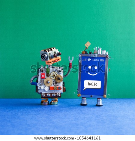 Friendly mobile smartphone gadget robot. robotic toy character, creative design touch screen phone device, light bulb capacitors sim card. Sms message Hello, smiley face on blue. Green background