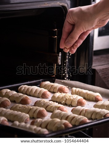 Baking oven: the baker sprinkles buns with sesame seeds before baking in the oven.