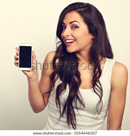 Happy smiling beautiful excited woman holding and advertising mobile phone on white background with empty copy space. Closeup portrait