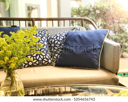 Yellow flowers in vase decoration on the table with vintage pattern pillows in living room, vintage decoration style