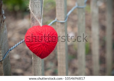 closeup of red woolen heart in outdoor on wooden fence
