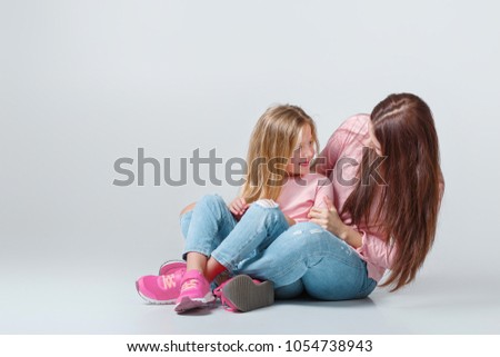 young mother and daughter having fun together on pink background