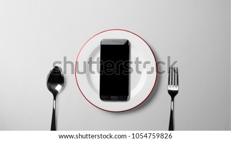 Black smartphone on white plate on white background with copy space