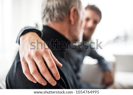 Unrecognizable hipster son and his senior father at home. Royalty-Free Stock Photo #1054764995