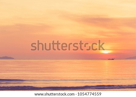 The beautiful sunset landscape, the turquoise sea and the orange sky over it with amazing sunlight reflected in the calm waves. There are beautiful mountains in Thailand.