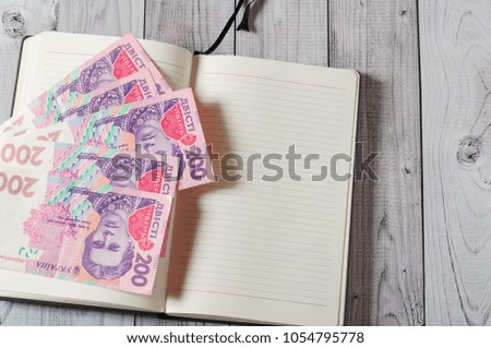 Notepad, pen and money on a light wooden background