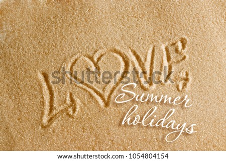 The word love is painted on the sand and the inscription is summer holidays. Beach background. View from above. The concept of summer, summer kanikkuly, vacation, holydays.