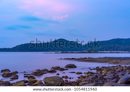 the smooth sea with many rocks, mountain and a single tree at twilight. this picture takes from kood island, tak province, thailand.