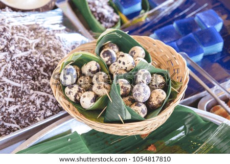 The quail eggs in the basket are wrapped in banana leaves for sale.