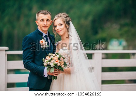 bride and groom in carpathians, mountains, beautiful nature, landscape, scenery. Newlyweds at mountain terrace. Windy veil. Tender picture.