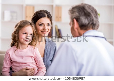 Pediatrician doctor examining child. Mother holding baby in her hands.