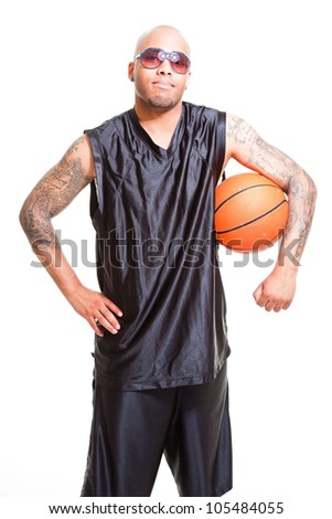 Studio portrait of basketball player wearing black sunglasses standing and holding ball isolated on white. Tattoos on his arms.