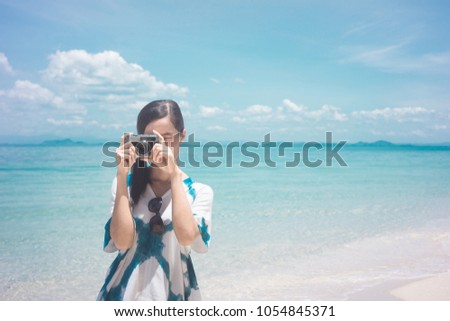 Soft focus Young woman using with vintage retro camera at the beach background