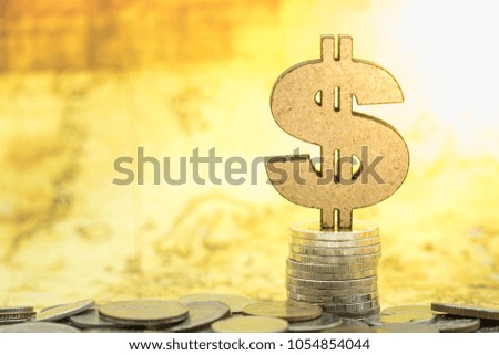Money Saving Concept. Wood dollar sign icon on stack of coins with world map as background.