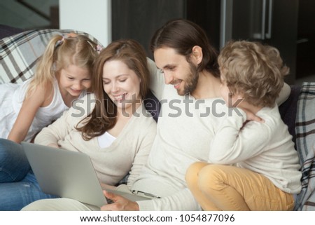 Smiling parents with kids using laptop on sofa, happy family with children son daughter having fun with computer doing online shopping or watching funny video together sitting on couch at home