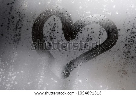 The heart is painted on the misted glass in the winter