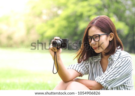 Portrait of young woman holding camera and taking photo at summer green park