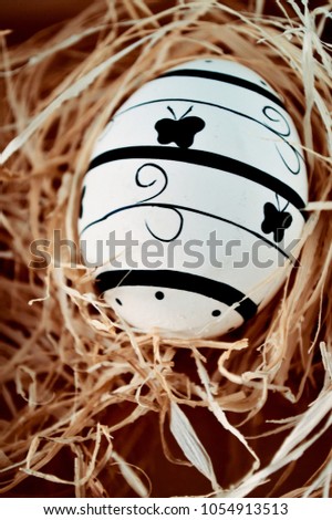 a black painted Easter egg with butterflies in the hay