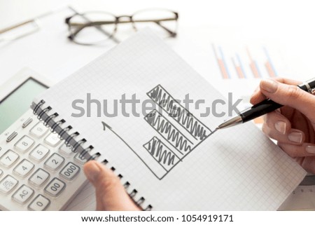 Businesswoman working on project about business growth. Drawing of a growing graph in notebook