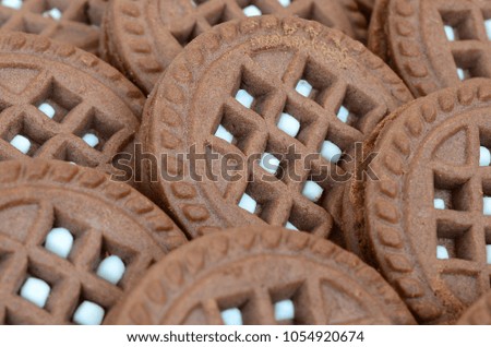 Detailed picture of dark brown round sandwich cookies with coconut filling close up. Background image of several treats for tea